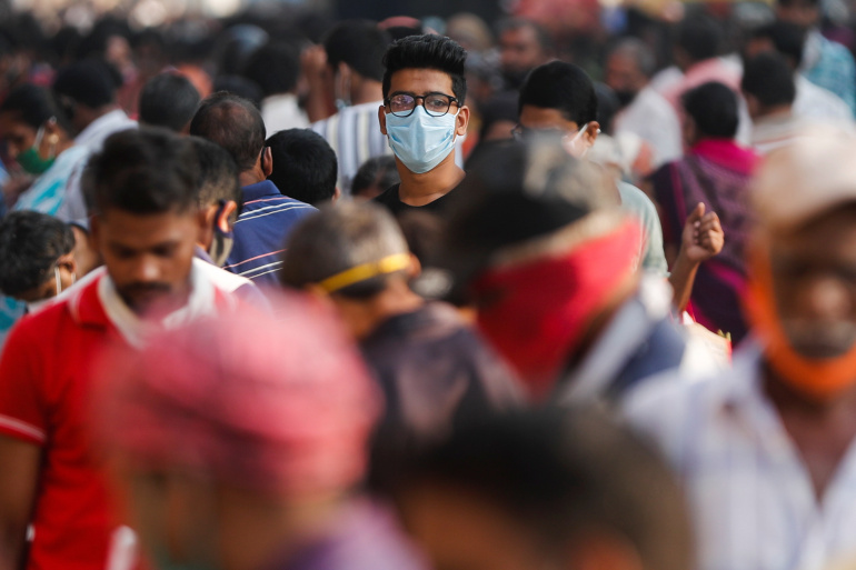 A man in India wearing a face mask at a crowded market after the spread of second wave